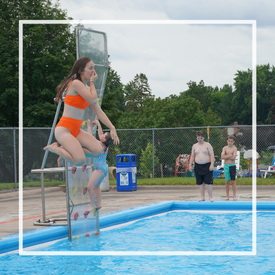 Young girl jumping off diving board into Northview Pool holding her nose