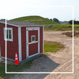 Small red building in front of a compost site